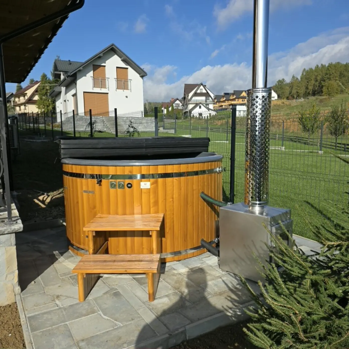 Wanna SPA ogrodowa z drewnianą obudową i piecem na drewno przy domu jednorodzinnym