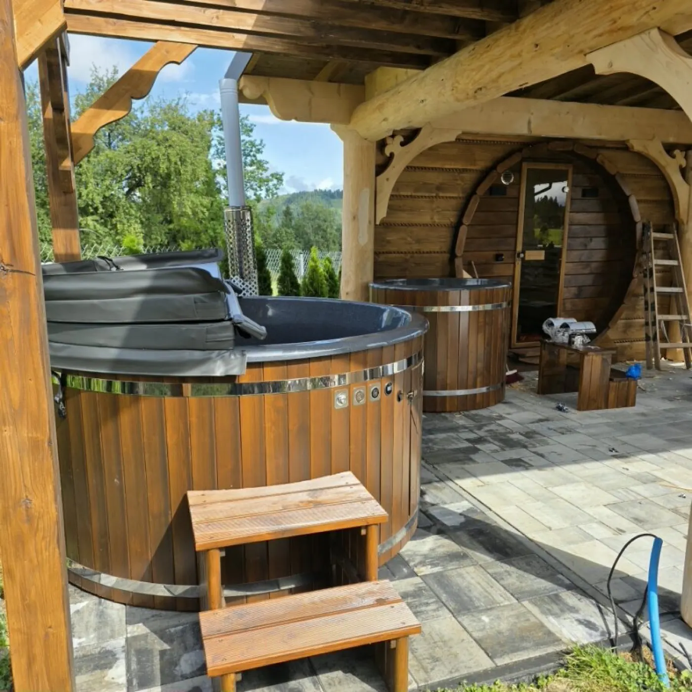 Wanna SPA ogrodowa pod drewnianą wiatą obok sauny beczki, z widokiem na góry