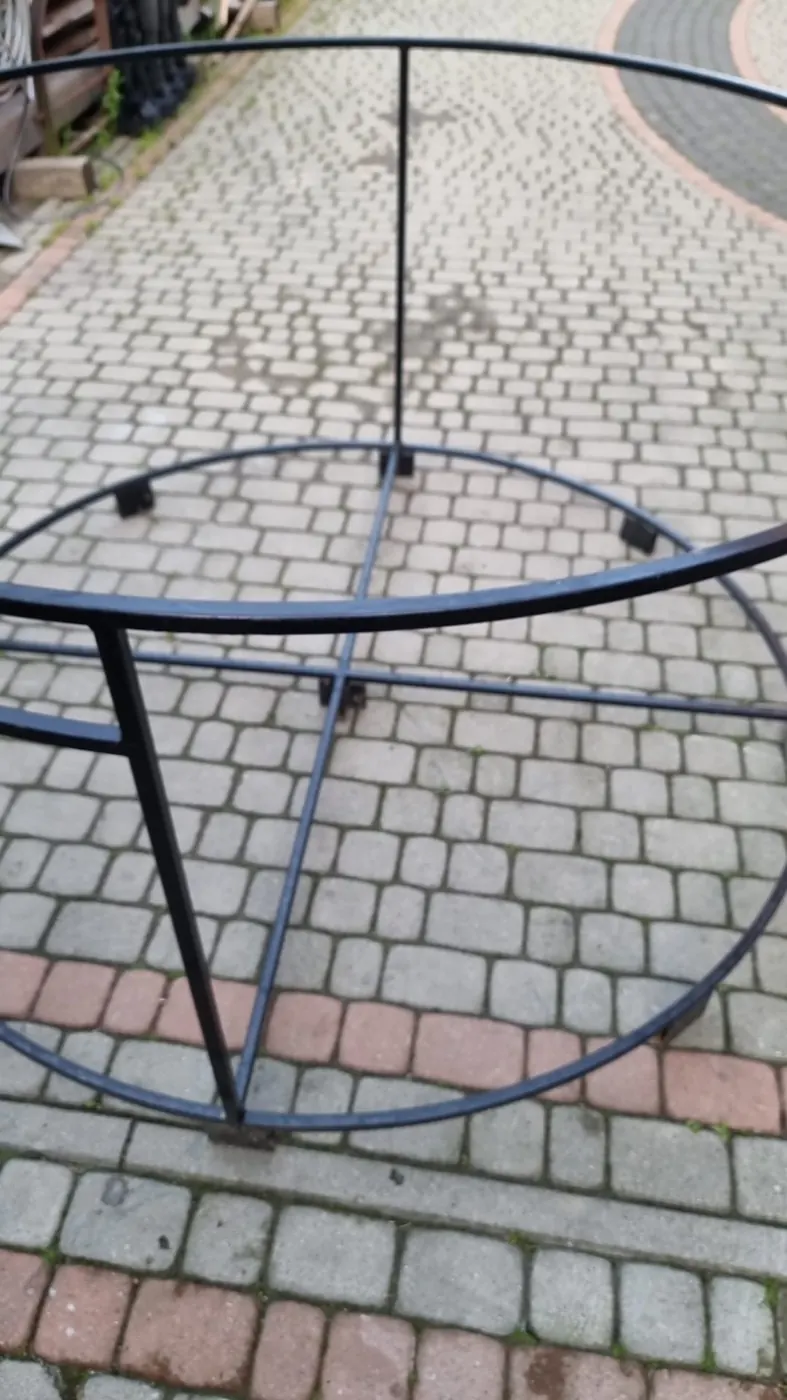 Stalowa konstrukcja nośna balii ogrodowej przed montażem, na kostce brukowej przed warsztatem